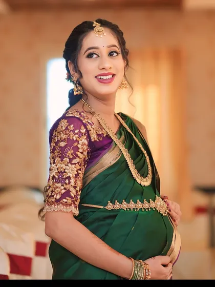 This purple net blouse was a joy to create for my dear client Sowmya's baby shower. The sheer sleeves are adorned with delicate, hand-embroidered floral vines in gold threadwork, creating a look of ethereal elegance for her special day.