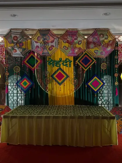 A grand Mehendi stage with floral arches, Rajasthani-style jharokhas, and a vibrant backdrop, creating a royal and festive look.