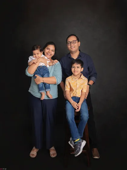 A picture-perfect family of four. This classic studio portrait with a simple dark background puts all the focus on the family's happy smiles and connection.