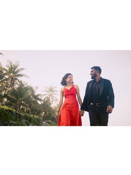 Walking hand-in-hand along the beach, this wide shot beautifully captures the couple against the vastness of the sky and palm trees.