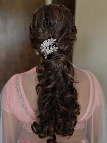 A beautiful curly ponytail with a sparkling floral hair clip. This is an elegant and timeless hairstyle for any special occasion.