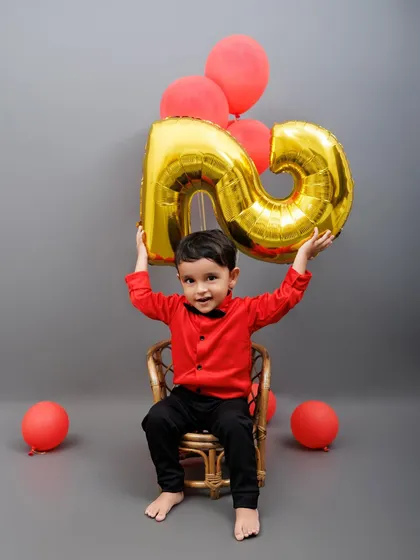 This happy two-year-old holds up a giant number "2" balloon, celebrating his birthday in style.