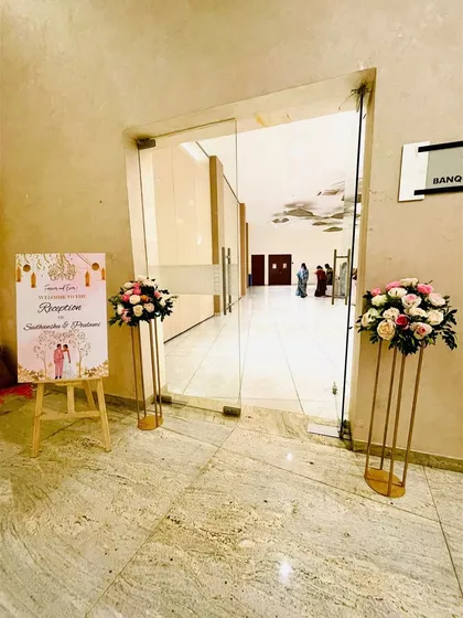 The welcome area for a minimal reception, featuring a custom sign on an easel and matching floral arrangements on pedestals to greet guests.