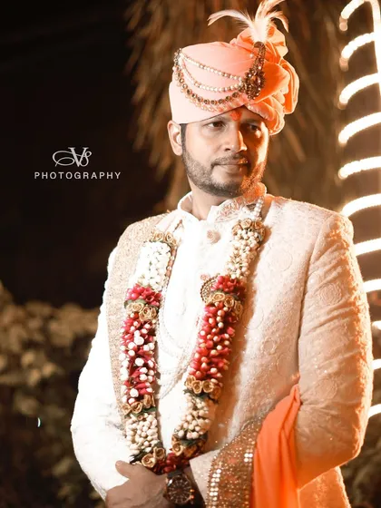 A classic groom portrait captured at night. The warm backlighting and the groom's confident pose in his elegant sherwani and safa create a striking and timeless image.