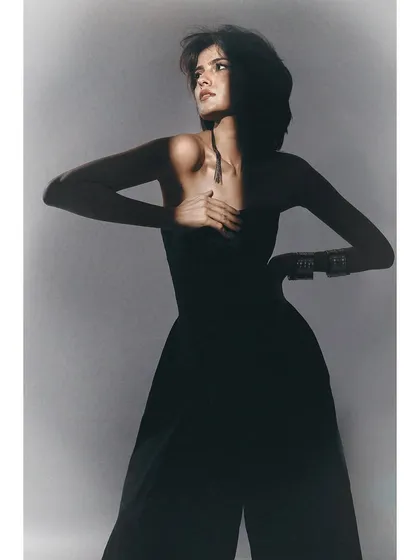 A black and white shot from the same series. The styling is simple, focusing on the model's form and the dramatic play of light and shadow across her body.