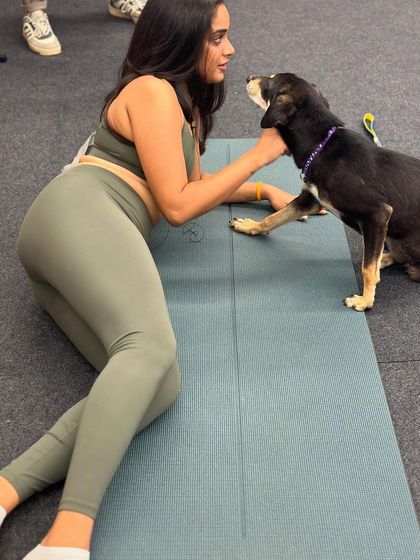 A participant takes a break from her yoga practice to connect with a friendly indie dog, who places a paw on her mat.
