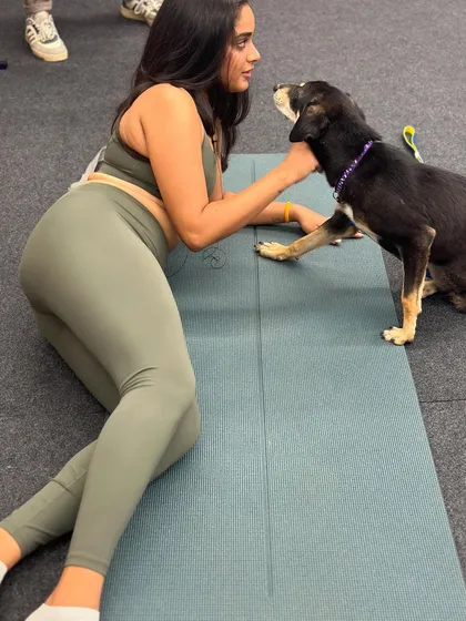 A participant takes a break from her yoga practice to connect with a friendly indie dog, who places a paw on her mat.