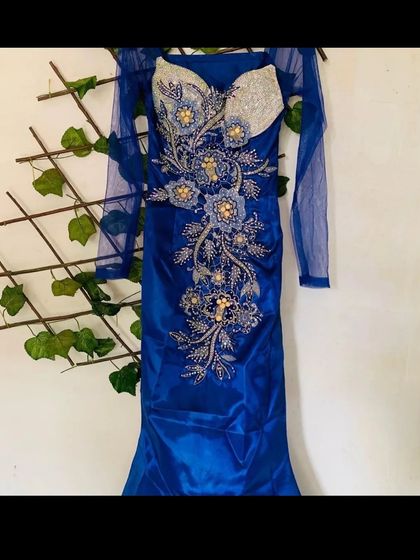A stunning royal blue bodycon gown with intricate silver and gold embroidery. The sheer sleeves add a touch of delicacy to this glamorous rental dress.