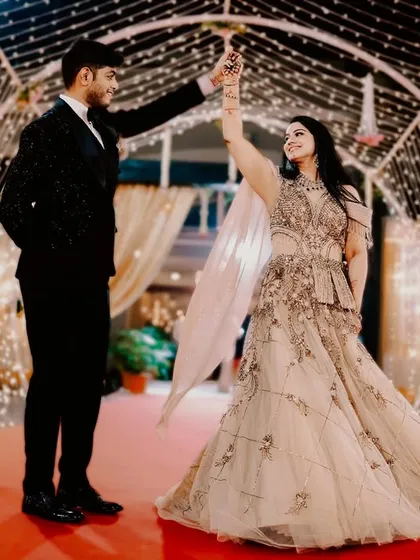 A fairytale moment as the couple dances under a tunnel of fairy lights. The bride's twirling gown and the magical lighting create a truly enchanting reception portrait.