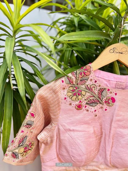 This Kalamkari patchwork blouse is a collaboration of Indian textile art and hand embroidery, featuring delicate floral motifs on a pink base.