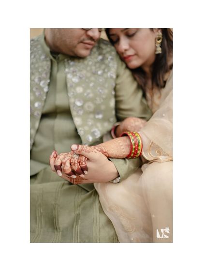 A close-up shot focusing on the couple's intertwined hands, showcasing her henna and bangles. This image is rich in detail and emotion, symbolizing their new bond.