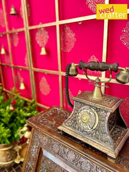 A vintage-style rotary telephone with intricate brass work sits on a carved wooden table, adding a unique, nostalgic touch to the decor.