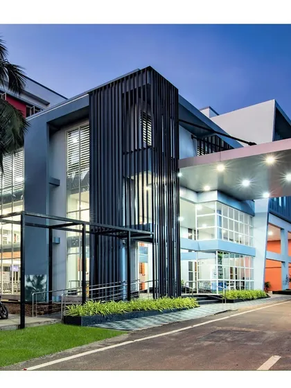 A close-up of the entrance of the Memorial Hospital, highlighting the use of vertical louvers and a large canopy. These elements provide sun shading and architectural character to the building's facade.