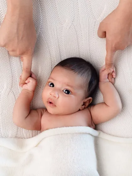 A sweet newborn holding onto their parents' fingers. This pose beautifully illustrates how their parents are their entire world.