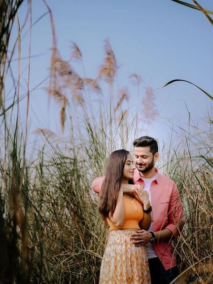 A romantic pre-wedding shot of Keshav and Priya in a field of tall grass, with a beautiful soft light creating a dreamy mood.