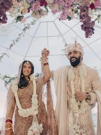 The triumphant and joyous exit of the couple after their wedding ceremony. Their happy expressions and raised hands tell a story of pure celebration.