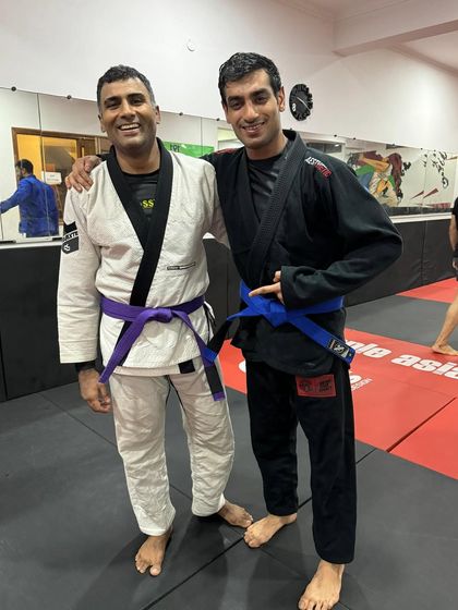 Two teammates, a purple belt and a blue belt, celebrating a promotion. We are all on this journey together, at different stages.