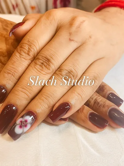 This design pairs a deep maroon gel polish with a stunning, hand-painted floral accent nail. The detail in the flower creates a sophisticated focal point for the entire set.