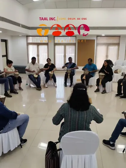 A wide shot of a training session in progress. Notice the circular setup, the variety of participants, and the facilitator guiding from within the circle. This is the classic drum circle environment we teach you to create.