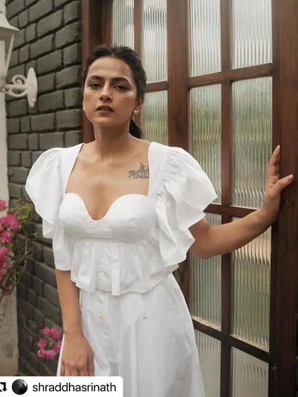 This shot showcases the full white outfit against a darker background, making the delicate details of the top and the flow of the Hridaya Pants stand out.
