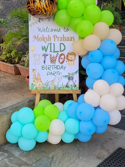 A personalized "Wild Two" welcome sign on an easel, framed by a balloon arrangement. This is the first thing guests see and sets the tone for the party.