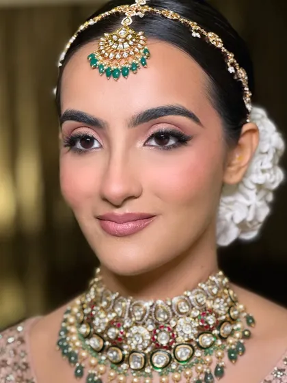 A close-up of the flawless bridal glam on my doctor bride. The makeup features soft, blended eyeshadow and a natural pink lip, complementing her pastel lehenga and intricate polki jewelry.