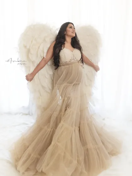 A joyful and expressive portrait of the mother-to-be with the angel wings. Her pose, with arms outstretched, conveys a sense of freedom and happiness.