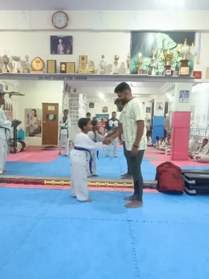 A young student receives his blue belt with a respectful handshake.