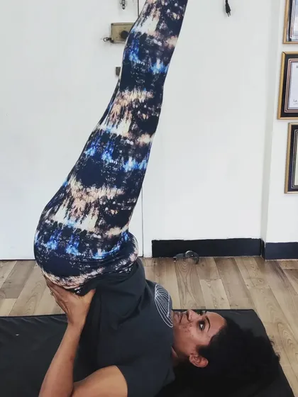 A student holds Sarvangasana (Shoulder Stand), often called the 'queen of asanas'. This inversion calms the nervous system, improves circulation, and brings a fresh supply of blood to the upper body and brain.