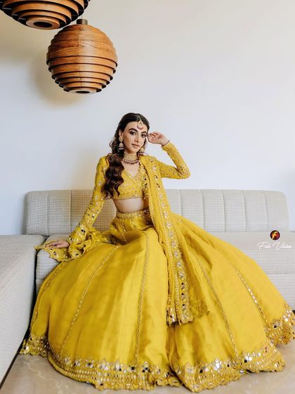 A full-length portrait of the bride in a stunning yellow lehenga, looking radiant and poised during her Mehendi ceremony.