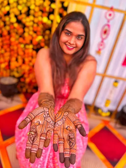 A smiling client happily presenting her beautiful peacock mehndi design.