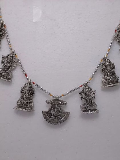 A German silver door hanging (toran) with small idols of Ganesha and Lakshmi, perfect for welcoming positive energy into your home.