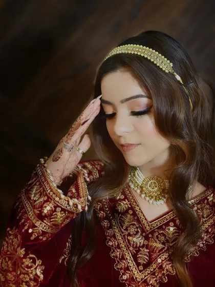 A graceful salaam pose that beautifully showcases the detailed embroidery on the sleeves of the traditional Kashmiri pheran. The focus is on the cultural gesture and the rich attire.