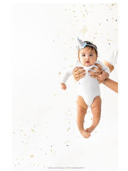A full portrait version of the confetti celebration. Being held securely in loving hands while looking at the camera creates a feeling of safety and joy.