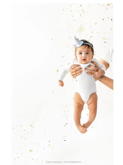 A full portrait version of the confetti celebration. Being held securely in loving hands while looking at the camera creates a feeling of safety and joy.