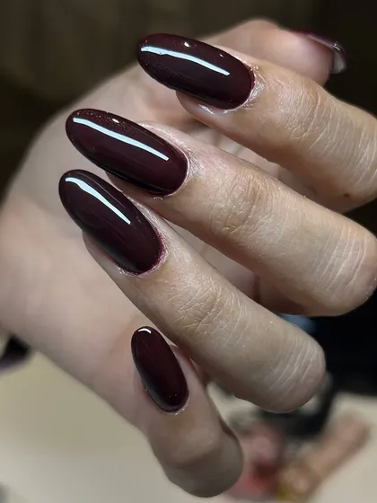 A deep, glossy burgundy on long, oval-shaped nails. This color is rich, dramatic, and impeccably applied.