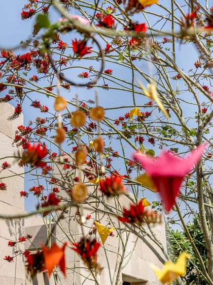A detail of the decor, with colorful paper cranes and dried orange slices hanging from tree branches, adding a touch of handcrafted charm.