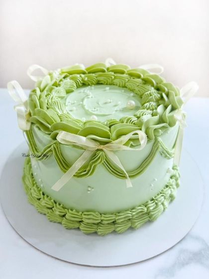A pastel whisper of sweetness. This vintage-style cake in a lovely shade of green features intricate buttercream piping and delicate ribbon bows.
