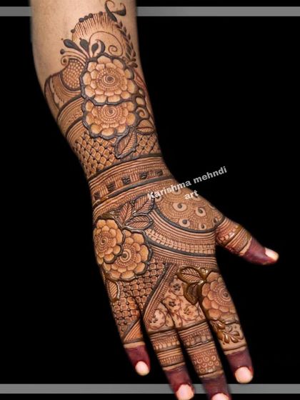 A detailed look at the back of a hand adorned with an intricate floral and patterned design. This single-hand view highlights the complexity and artistry involved in a full bridal mehendi.