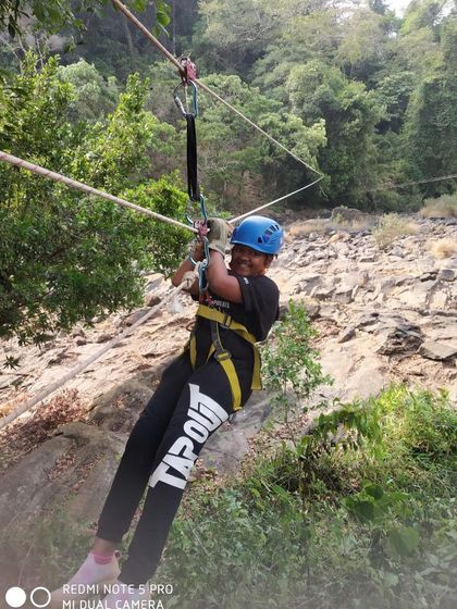 A smiling camper enjoys the thrill of the rope bridge activity at our Barapole camp.