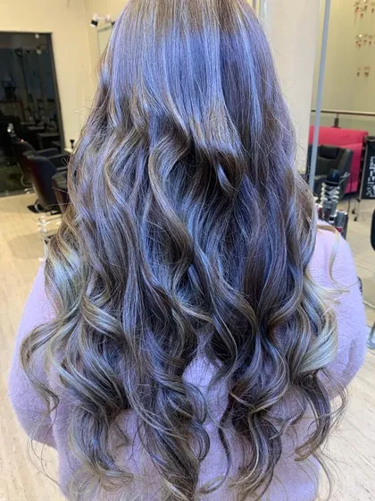 This is a perfect example of a cool-toned balayage with soft, beachy waves. We specialize in creating these custom-blended looks that grow out beautifully and give the hair a natural, sun-kissed dimension.