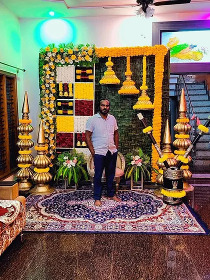 Another shot of the vibrant hall decoration for a housewarming, featuring hanging temple bells and marigold flowers.