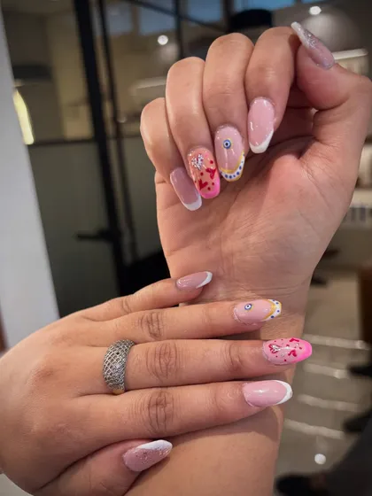 Let's get creative with your nail art! This set combines classic French tips with pops of pink, delicate hearts, and a protective evil eye charm. Your nails can tell a story, and I'm here to help you write it. 💖