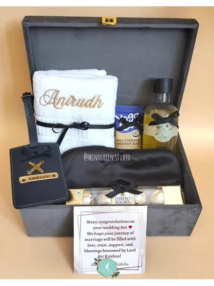 Celebrating the journey of two hearts becoming one is a true joy. This wedding hamper, housed in a sophisticated grey suede box, features personalized towels embroidered with the couple's names, matching custom luggage tags, Ferrero Rocher chocolates, and a relaxing eye mask. It's the perfect way to congratulate the happy couple.