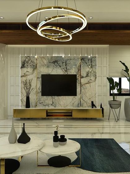 The living room of "Yash Villa," featuring a bookmatched marble TV wall, a modern ring chandelier, and a mix of neutral tones with a pop of blue from the rug.