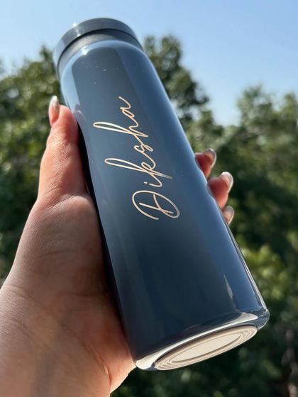 A closer look at our personalised mini flask, showing the elegant script font we use to add your name. It's the perfect size to slip into your bag for work or the gym.