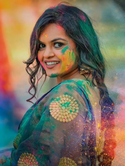 A close-up portrait from the Holi shoot, capturing a bright smile amidst a cloud of colors.