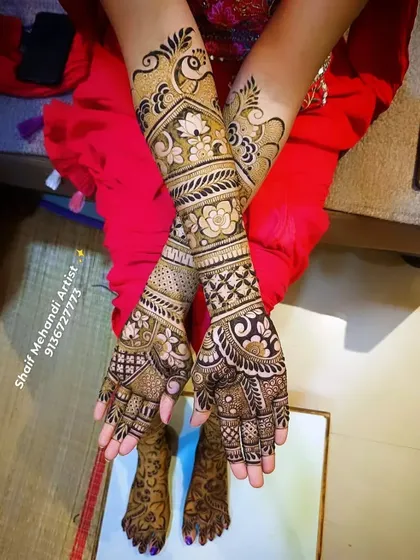 A beautiful bridal design featuring a prominent peacock on the forearm, surrounded by floral and geometric patterns.