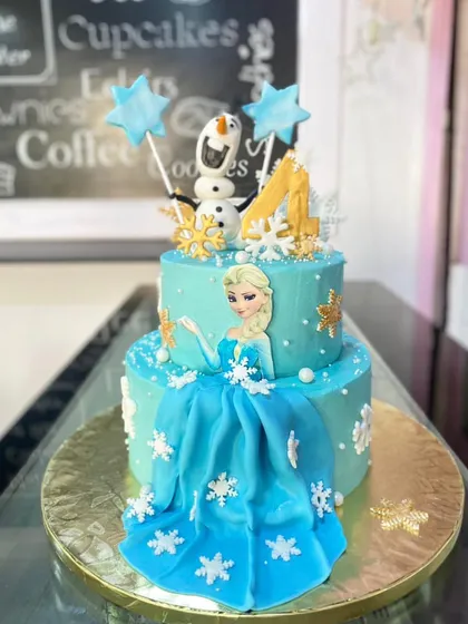A beautiful two-tiered cake inspired by Disney's Frozen. This design features Queen Elsa, a flowing fondant dress, and delicate snowflake details.