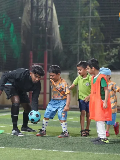 A coach works closely with a group of young players, teaching them a new drill with patience and encouragement.